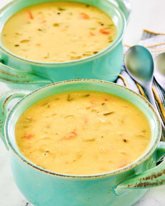 Homemade cheddar cheese soup in two soup crocks.