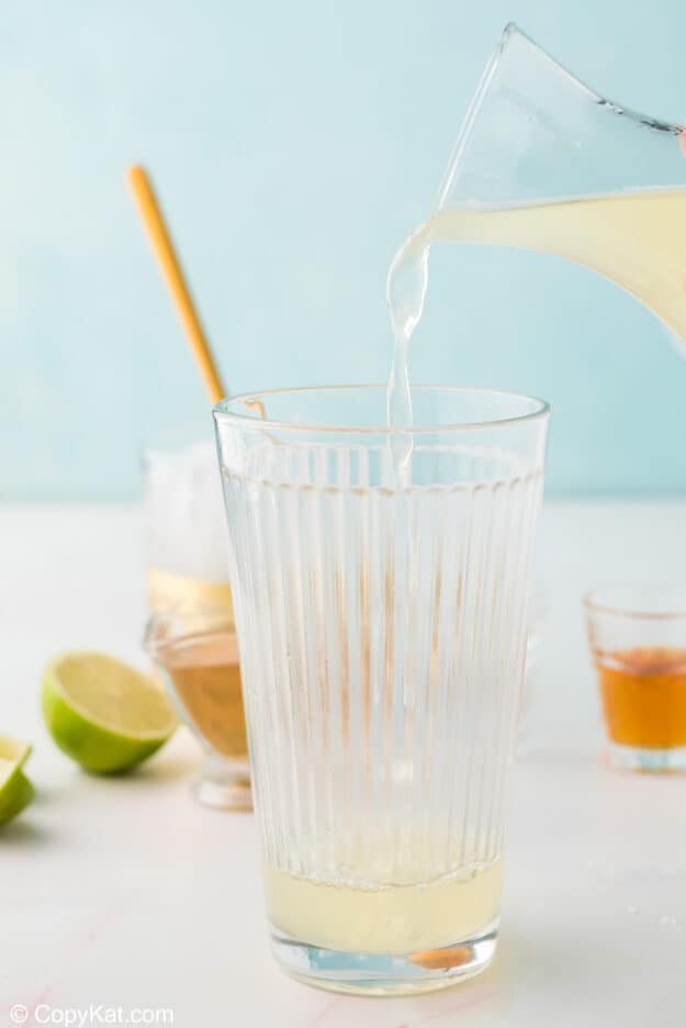 Pouring sour mix into a glass to make a Chili's Presidente margarita.