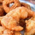 Closeup of homemade Long John Silver's chicken planks and onion rings on a blue plate.
