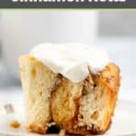 Homemade cinnamon roll with cream cheese frosting on a plate.