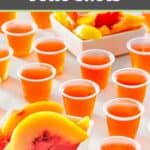 Peach jello shots in small plastic cups and peach slices in bowls.
