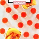 Overhead view of peach jello shots and peach slices.
