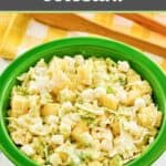 Pineapple coleslaw in a green bowl and a yellow checkered napkin.