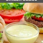A bowl of copycat Smashburger smash sauce beside a burger.