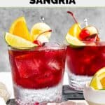 Homemade Applebee's red apple sangria in two glasses garnished with apples and fruit.