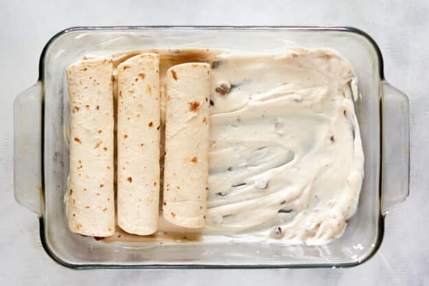 Assembling a burrito casserole in a baking dish.
