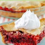 Closeup of fruit of the forest pie slice with whipped cream on top.