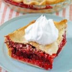 A slice of fruit of the forest pie with a dollop of whipped cream on top.