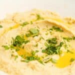 Closeup of homemade garlic hummus in a white bowl.