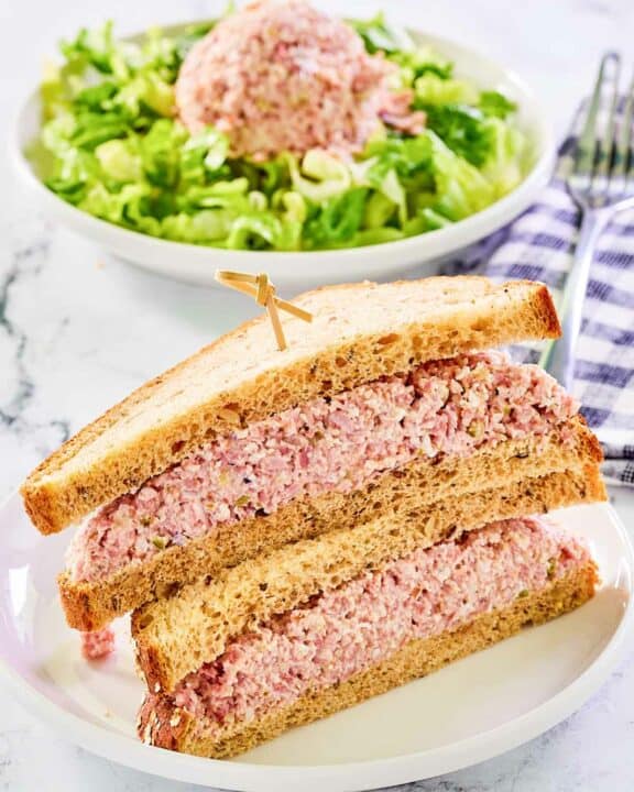 Ham salad sandwich and a scoop of ham salad on lettuce in a bowl.