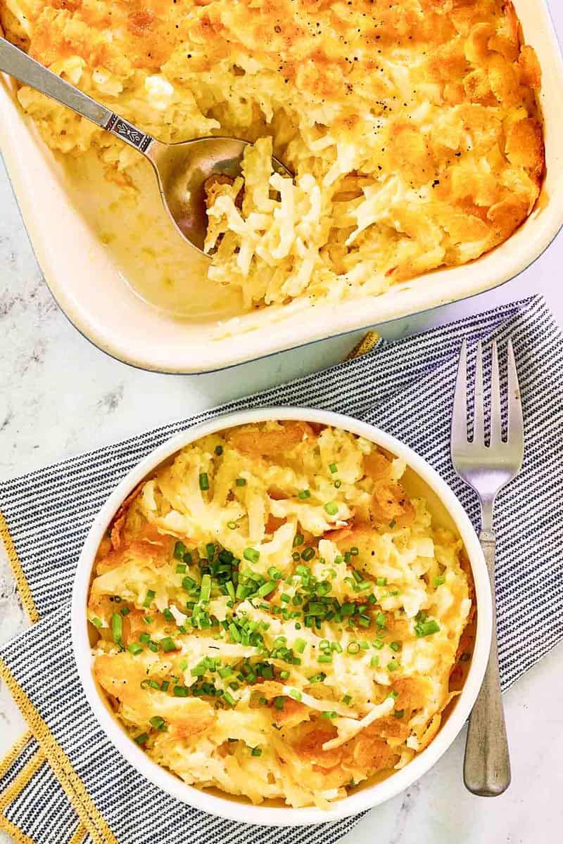 Overhead view of hashbrown casserole with cornflakes in a baking dish and bowl.