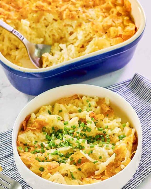 Hashbrown casserole with cornflakes in a baking dish and a serving in a bowl.