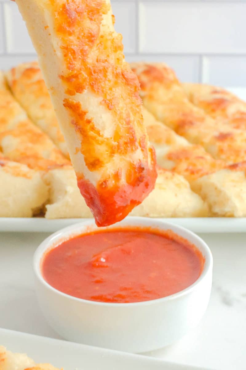 Dipping a copycat Pizza Hut cheese stick into marinara sauce.