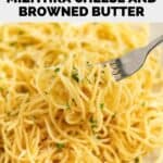Homemade spaghetti with mizithra cheese and browned butter on a fork over a plate of it.
