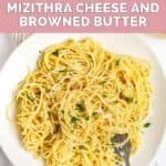 Overhead view of homemade spaghetti with mizithra cheese and browned butter and a fork on a plate.