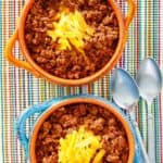 Overhead view of two bowls of Wick Fowler 2 alarm chili topped with cheese.