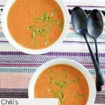 Two bowls of homemade Chili's chicken enchilada soup and two black spoons.