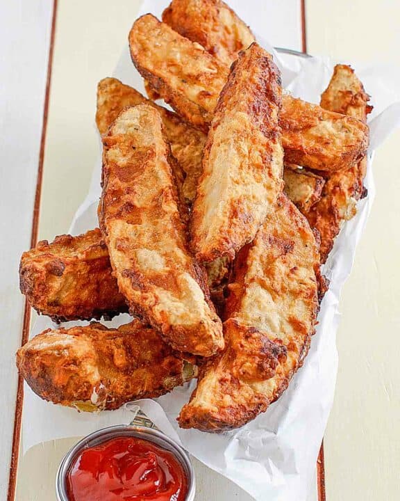 Jojo potato wedges in a serving basket and a cup of ketchup beside it.