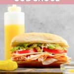 A sub sandwich and homemade Mr. Submarine sub sauce behind it.