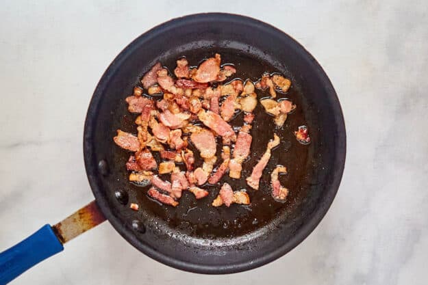 Cooked bacon pieces in a skillet.