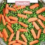 Buttery peas and carrots and a serving spoon in a skillet.