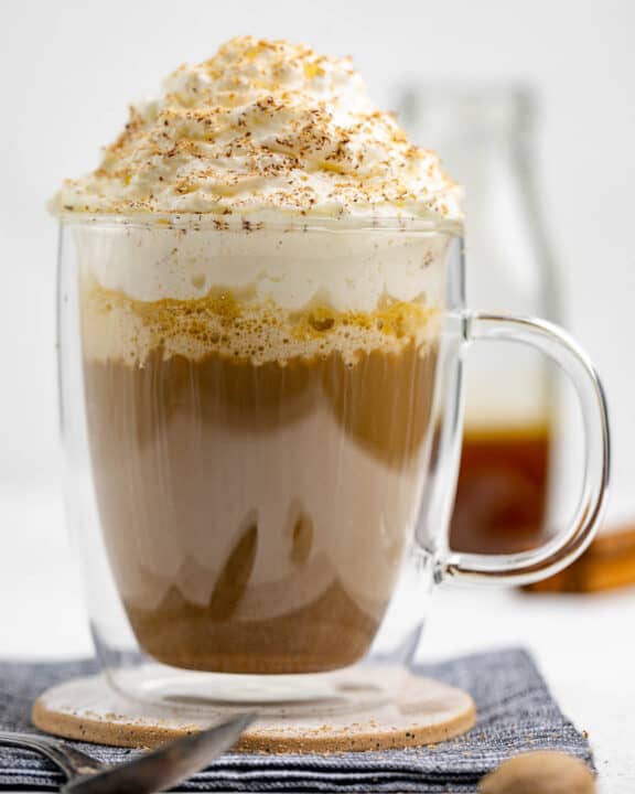 Copycat Starbucks pumpkin spice latte and pumpkin syrup behind it.