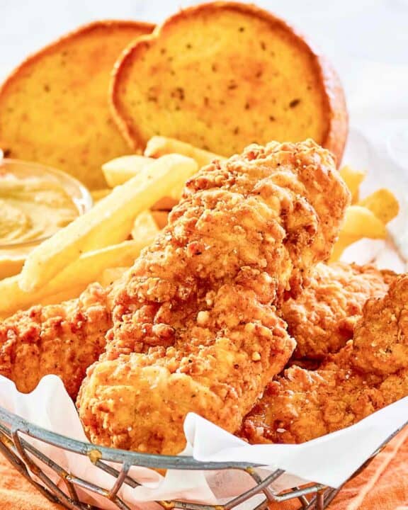 Copycat Whataburger chicken strips, fries, toast, and dipping sauce in a basket.