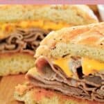 Homemade Arby's beef and cheddar sandwich cut in half and on a wood board.