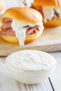 Copycat Arby's horsey sauce and roast beef sandwiches behind it.