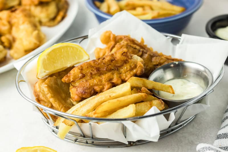Beer battered fish and chips in a parchment paper lined wire basket.