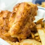Beer battered fried fish and chips in a wire basket.