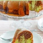 A slice of chocolate pistachio cake on a plate with the bundt cake behind it.