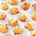 Homemade coconut macaroons spread out on a wood surface.