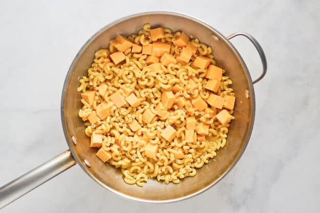 Cooked macaroni and cheese cubes in a pan.