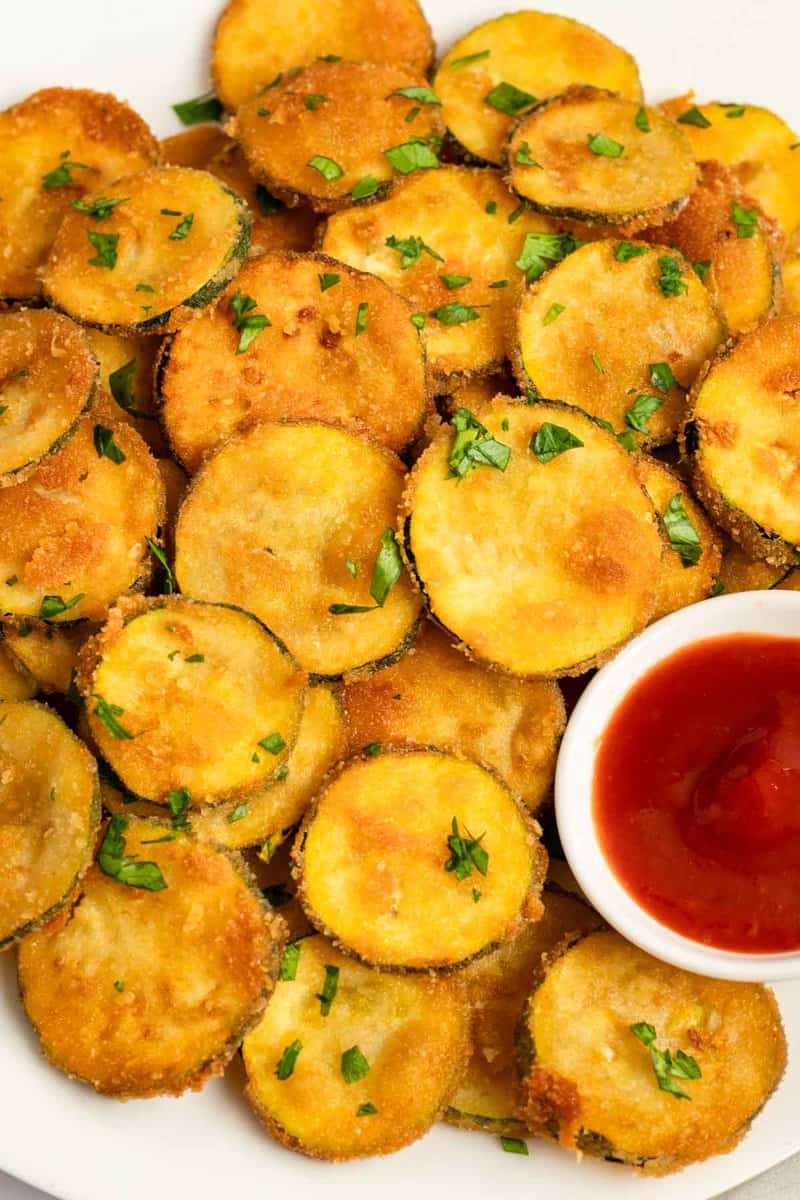 Fried zucchini and a bowl of marinara sauce.
