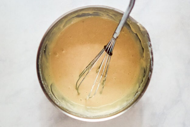 Buttermilk pancake batter and a whisk in a mixing bowl.