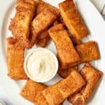 Copycat Pizza Hut Cinnamon Sticks and a bowl of cream cheese icing on a platter.