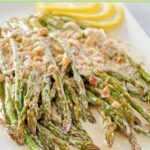 A platter with sauteed asparagus covered in lemon cream sauce.
