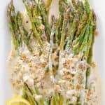 Sauteed asparagus spears with lemon cream sauce on a platter.