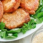 Homemade shake and bake pork chops on a platter and a bowl of the coating.