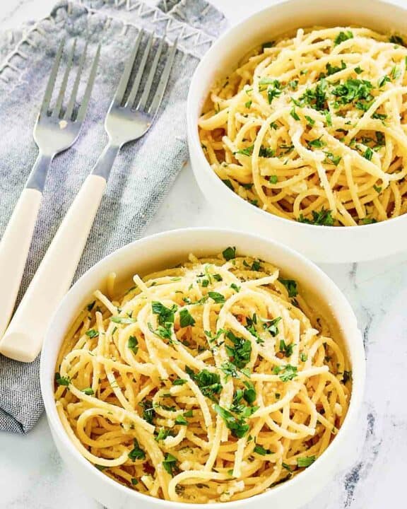 Two bowls of copycat Spaghetti Warehouse spaghetti with garlic butter.