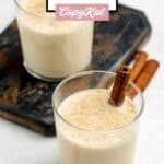 Two glasses of homemade spiked eggnog and cinnamon sticks.