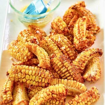 Air fryer corn ribs and a bowl of garlic butter on a platter.