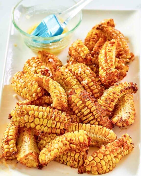 Air fryer corn ribs and a bowl of garlic butter on a platter.