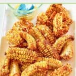A bunch of air fryer corn ribs and a bowl of garlic butter on a platter.