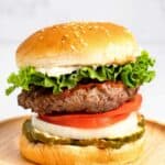 Homemade Burger King Whopper hamburger on a round wood board.