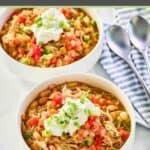 Two bowls of crockpot white chicken chili with beans and two spoons.