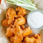 Copycat Hooters wings, a small cup of dipping sauce, and celery sticks.