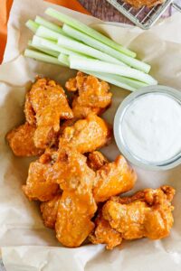 Copycat Hooters wings, a small cup of dipping sauce, and celery sticks.