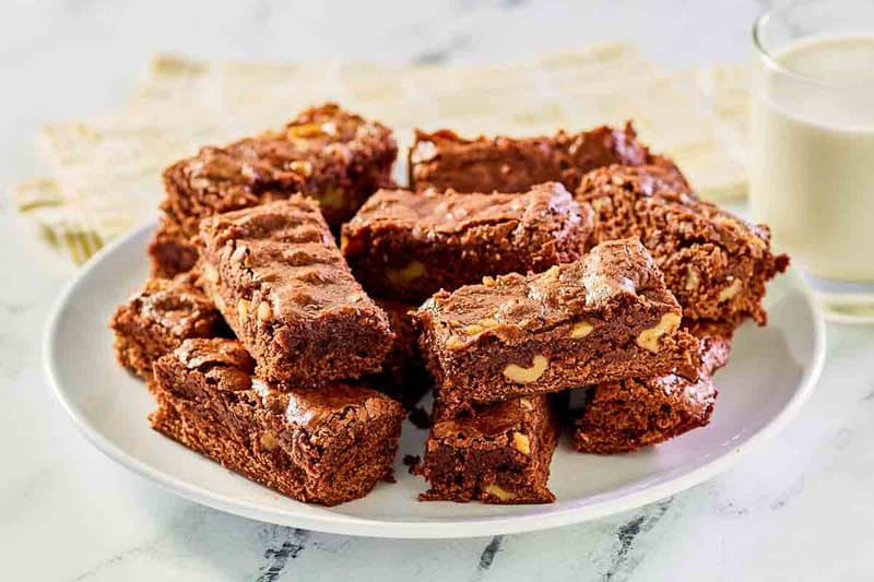 Homemade Kahlua brownies on a plate and a glass of milk next to it.